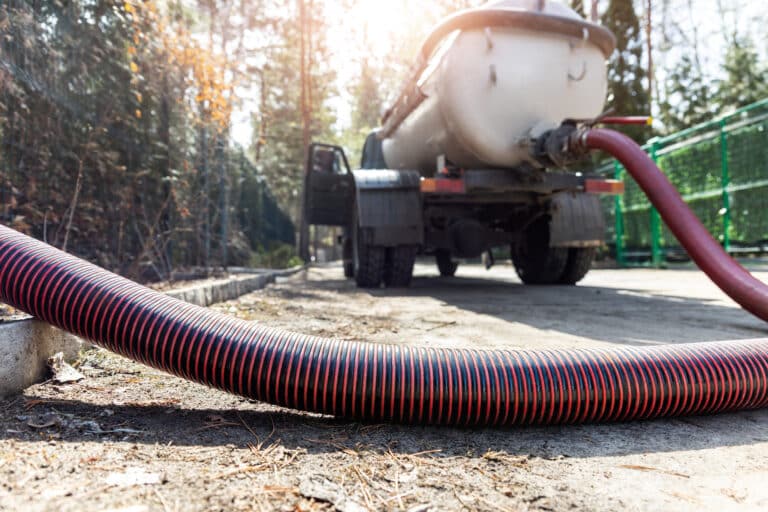 Close-up pipe hose of sewage truck car engine emptying home sewerage tank in Summit County